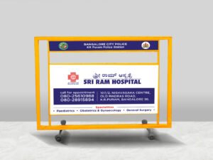 A Sriram hospital sign prominently displayed on a barricade, indicating the facility's location and services available.